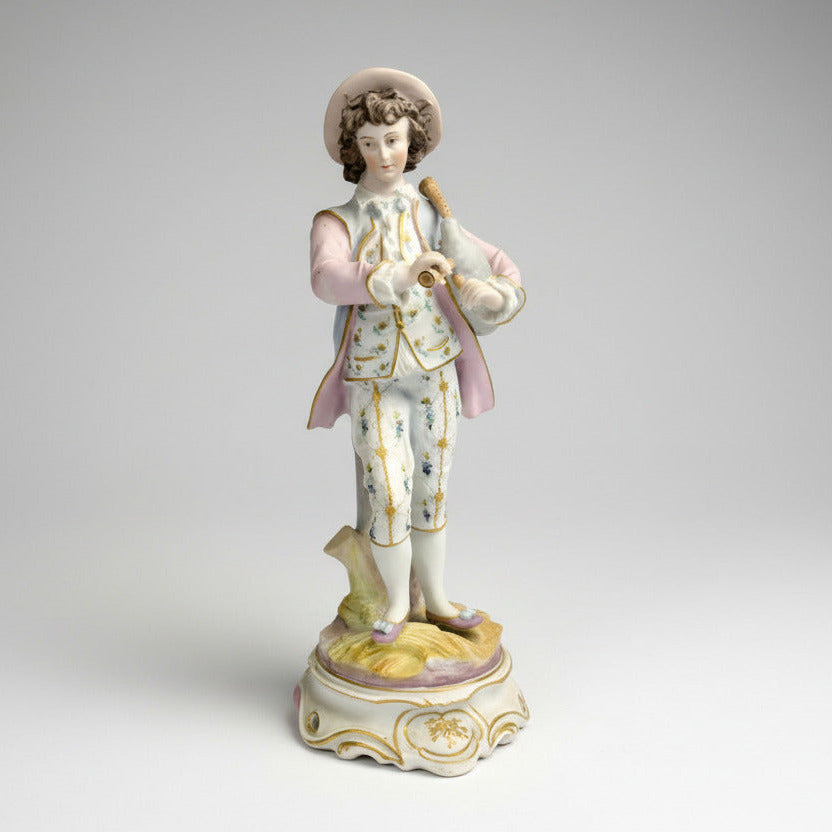 A bisque porcelain figurine of a shepherd with bagpipes, predominantly in pastel colors, on a decorative base.