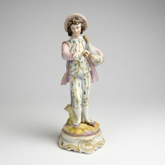 A bisque porcelain figurine of a shepherd with bagpipes, predominantly in pastel colors, on a decorative base.