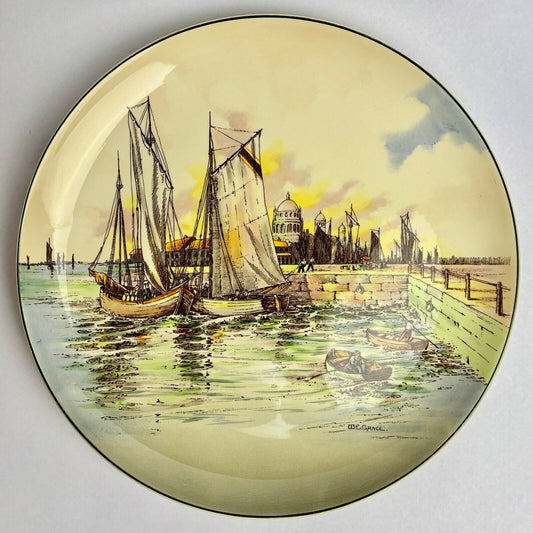 A round, multicolored ceramic plate featuring a nautical theme with a harbor scene, including boats and a lighthouse, signed by an unidentified artist.