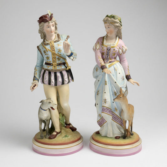 A pair of 20th century hard paste porcelain figurines featuring a gentleman in a colorful outfit and a lady in a pink dress with a dog and a fawn on a naturalistic plinth base.