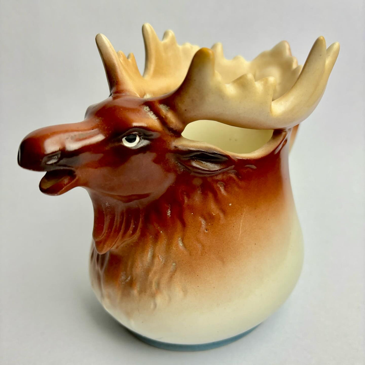 A ceramic pitcher in the shape of a moose with a brown and beige color scheme.