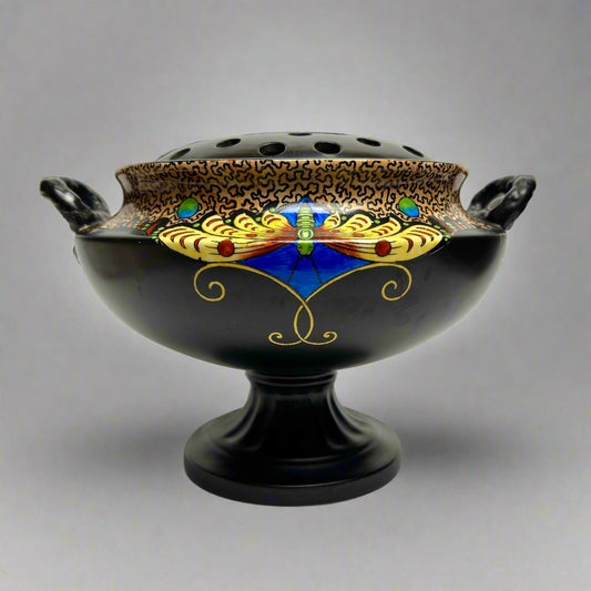 Decorative black bowl with gold, blue, and red patterns on a gray background
