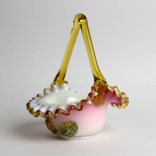 An antique Victorian Vaseline Uranium Basket with a white and pink floral pattern and a gold-colored handle.