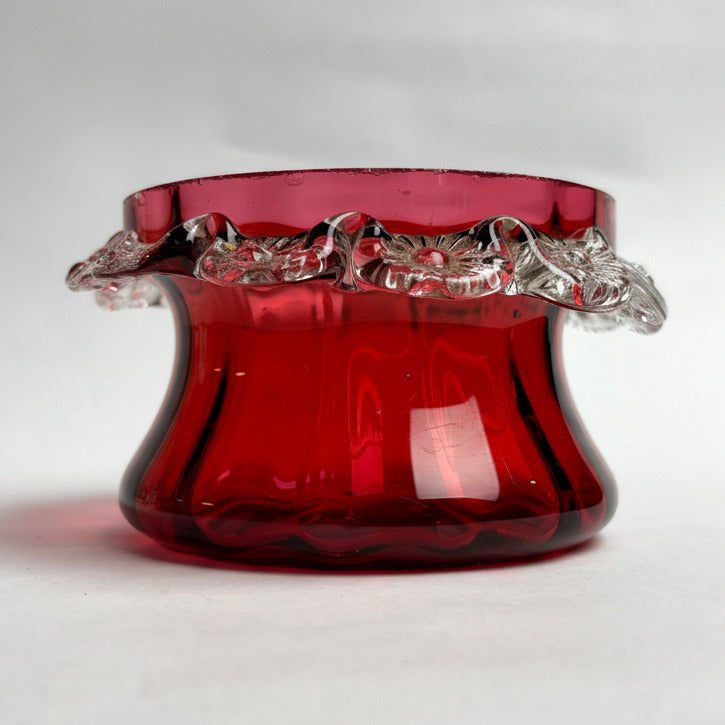 Red glass bowl with decorative rim on a white background