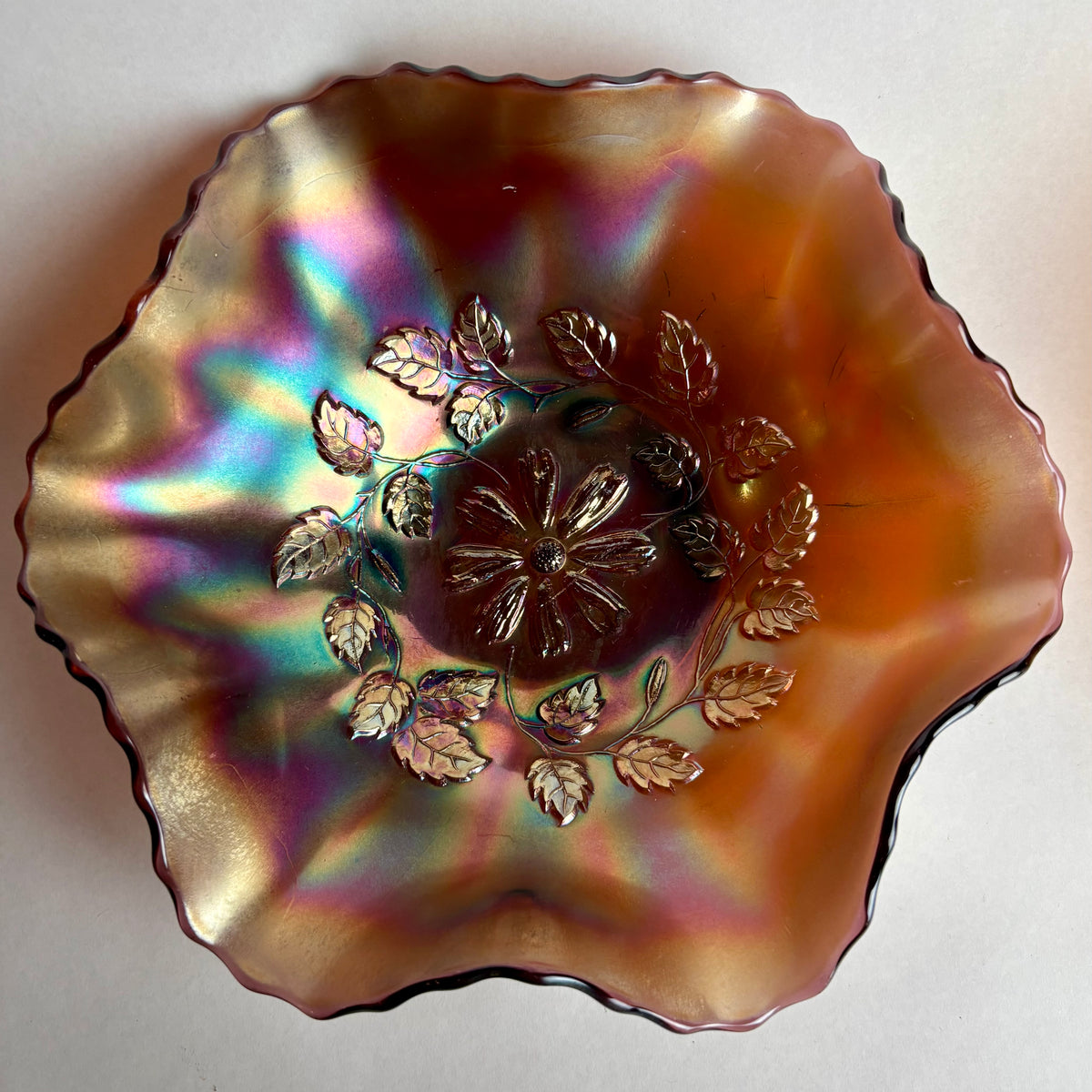 Decorative glass bowl with floral design and iridescent finish on a white background