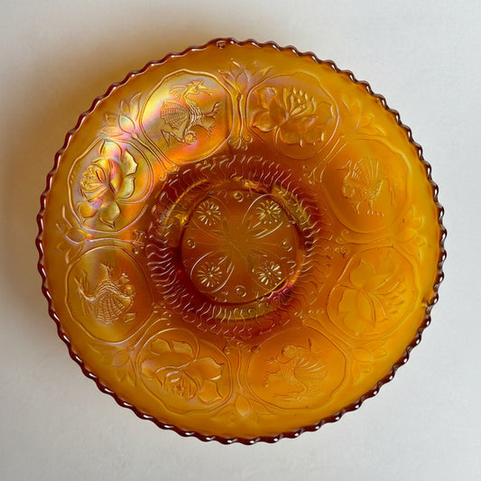 Decorative amber glass plate with embossed designs on a white background