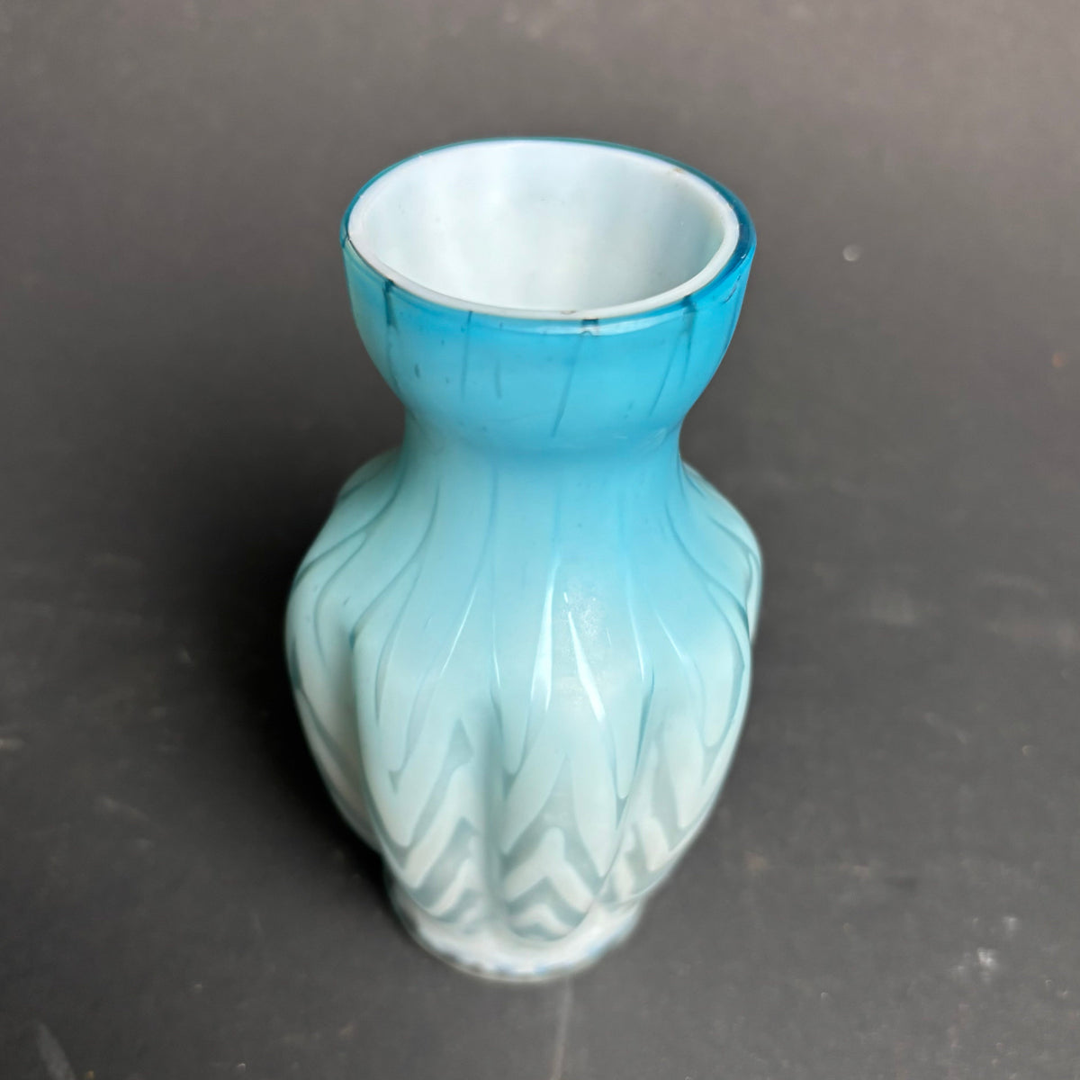 Blue ceramic vase with a textured design on a dark gray background