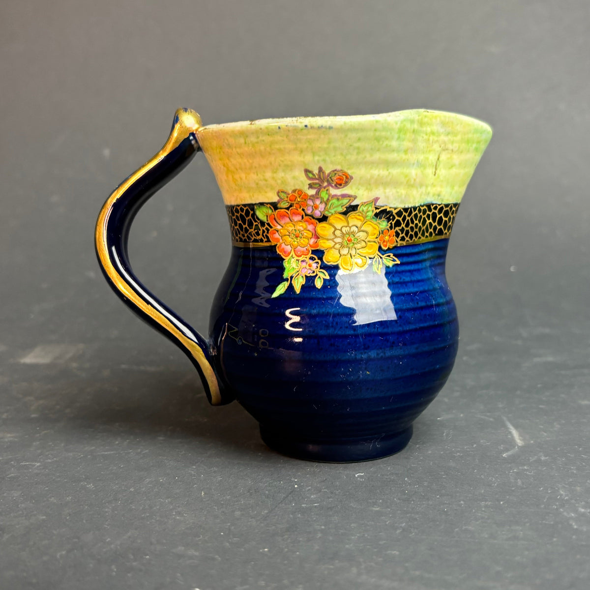 Ceramic pitcher with floral design on a gray background