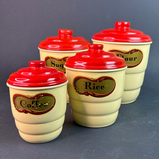 Set of four ceramic storage jars with red lids on a gray background