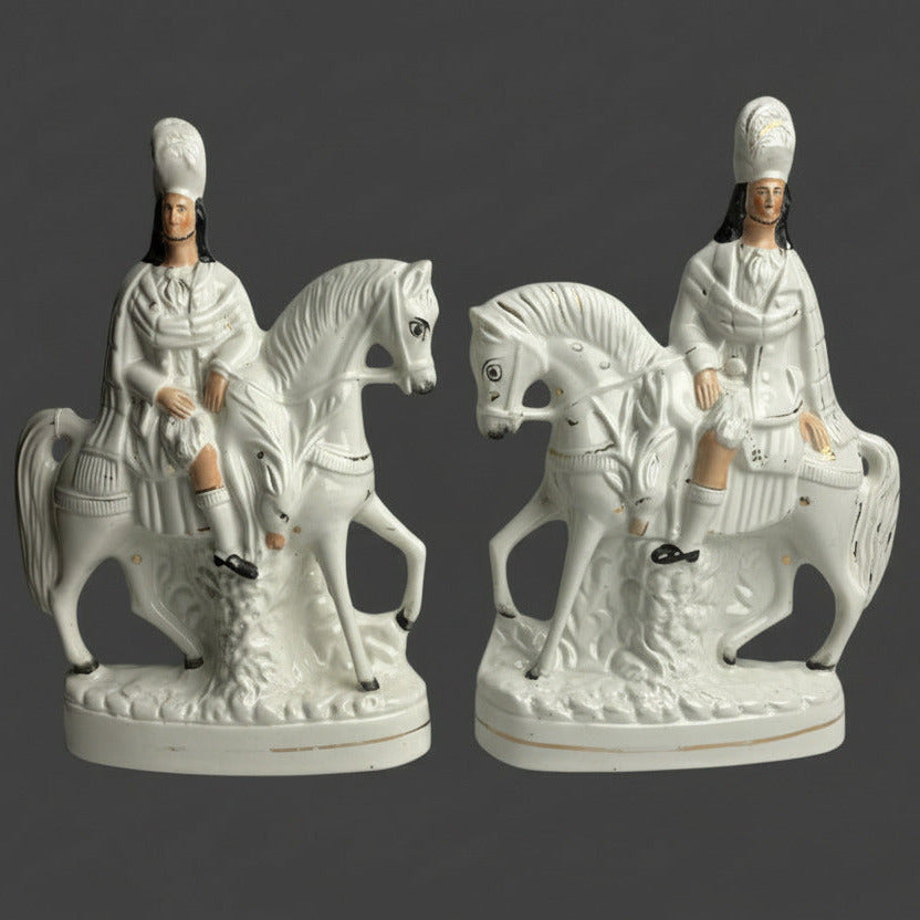 A pair of white ceramic figurines depicting Victorian Scottish Highlander hunters on horseback.