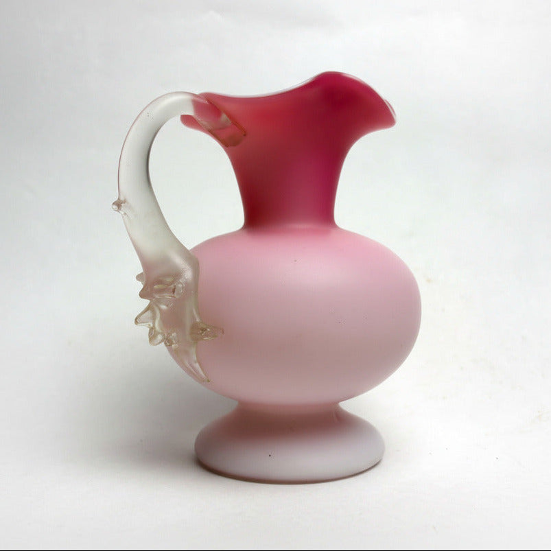 Antique satin glass jug with a pink body and white fluted top, featuring a thorn handle.