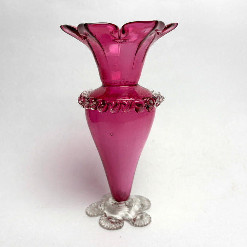 Pink glass vase with decorative base on a white background