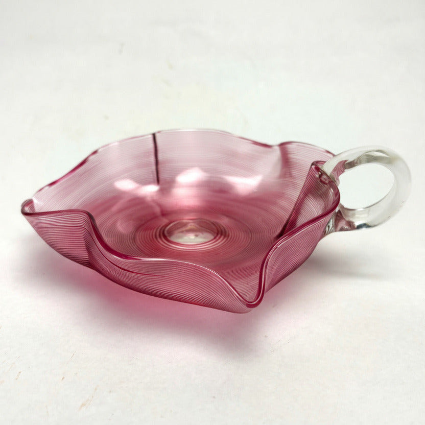 Pink glass dish with handle on a white background