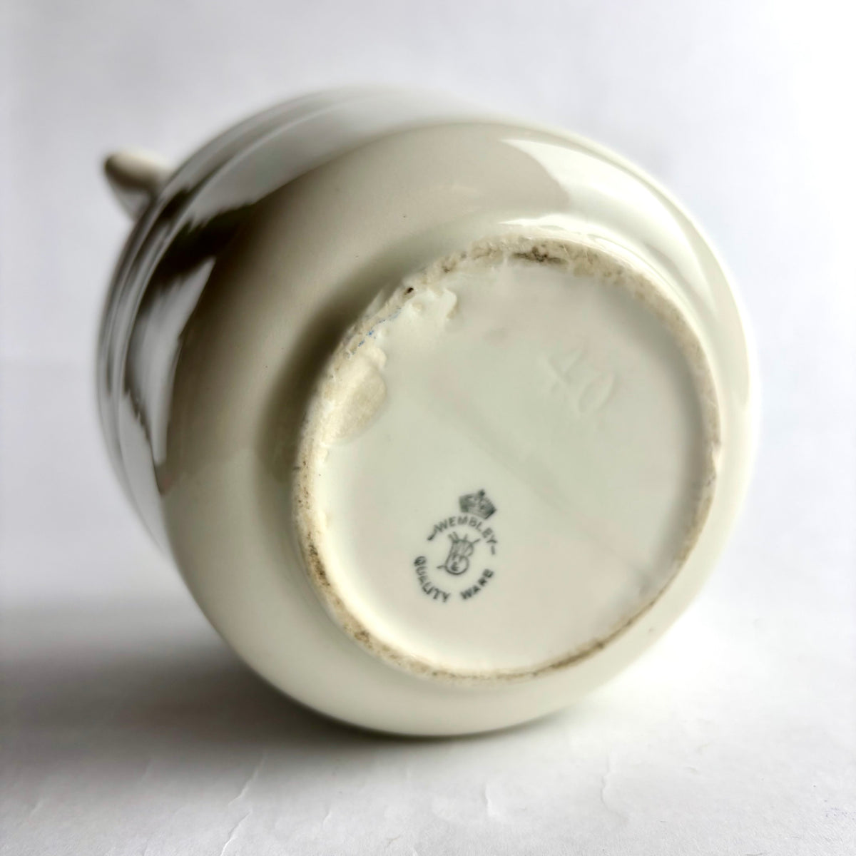 Close-up of a ceramic vase with a visible brand logo on a white background