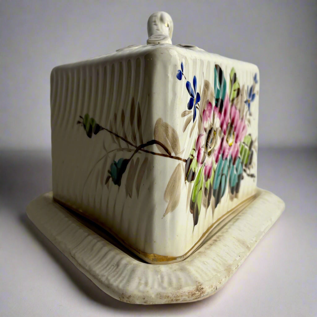 Ceramic butter dish with floral design on a plain background
