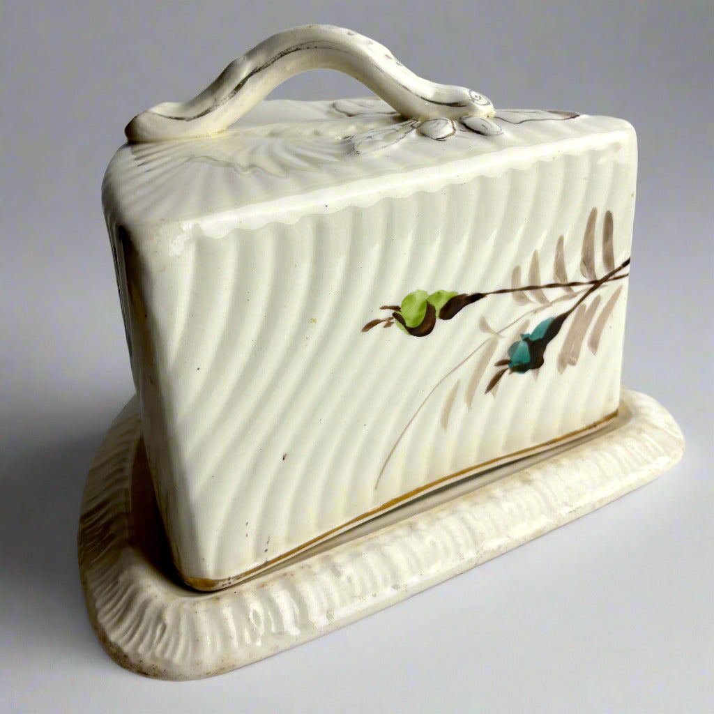Ceramic butter dish with lid featuring a design of leaves and flowers on a plain background