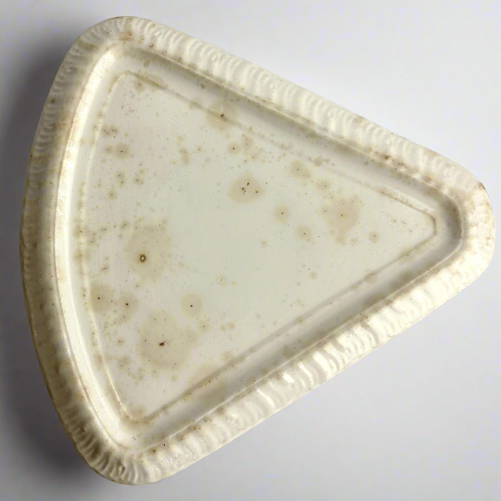 Triangular ceramic plate with a textured surface on a light gray background