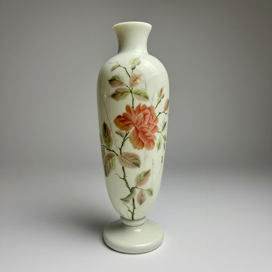 A tall, slender Victorian hand-painted milk glass vase with a floral pattern, predominantly pink and green colors, on a solid white background.