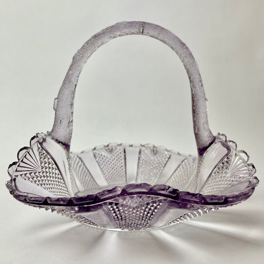 A purple amethyst glass basket with a floral pattern, showing some signs of wear.