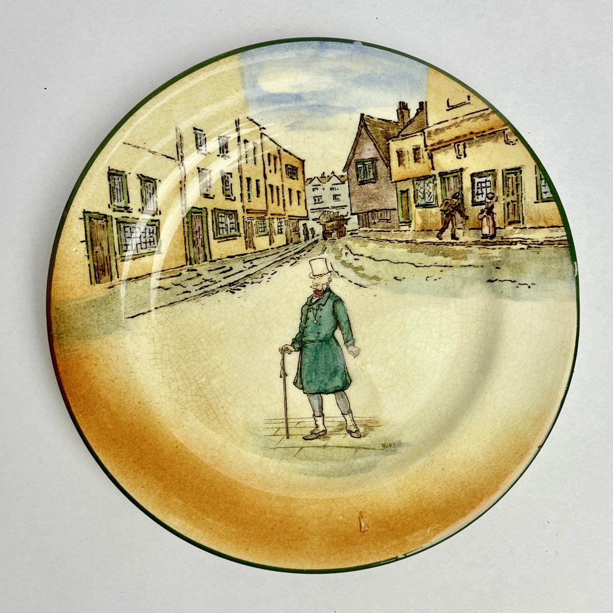 Decorative plate with a painted scene of a person walking on a street with buildings in the background.