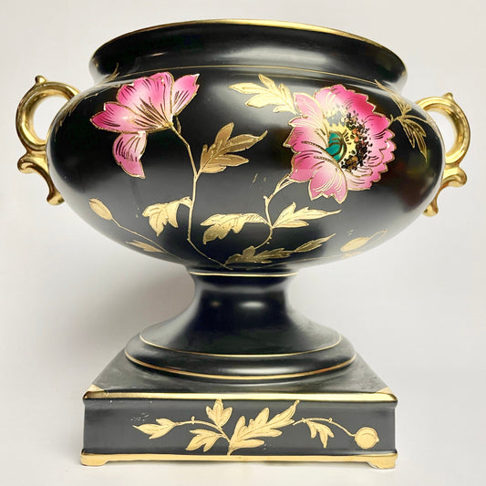 Decorative black vase with pink flowers and gold accents on a white background