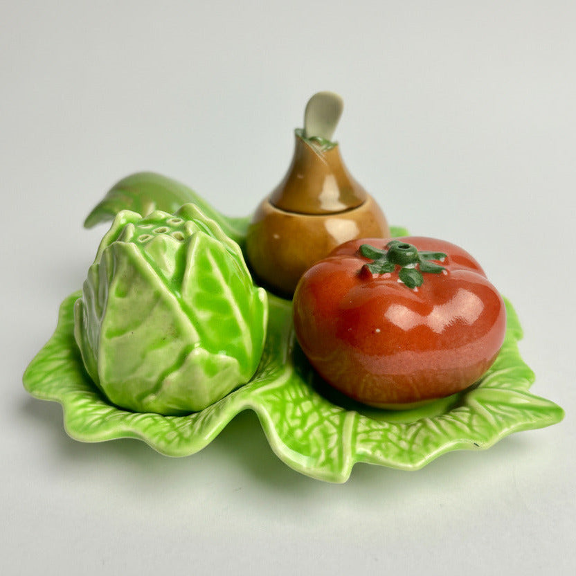 Decorative ceramic vegetables including a tomato, pear, and cabbage on a green leaf-shaped plate.