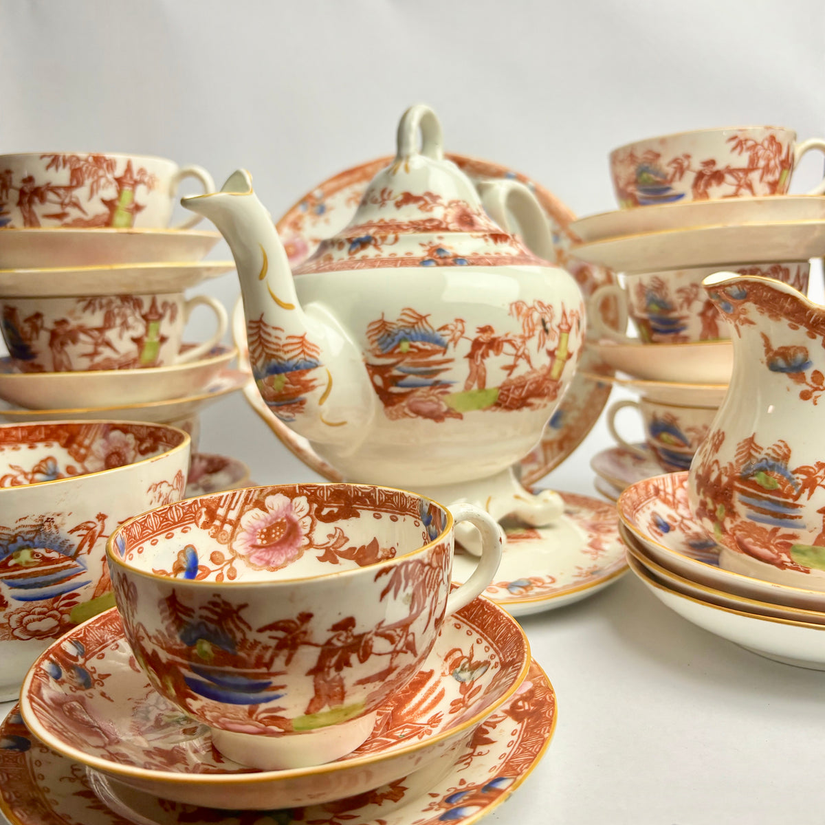 A 33 piece Georgian Hilditch & Sons Chinoiserie porcelain tea set featuring floral and animal patterns primarily in red, white, and gold colors.